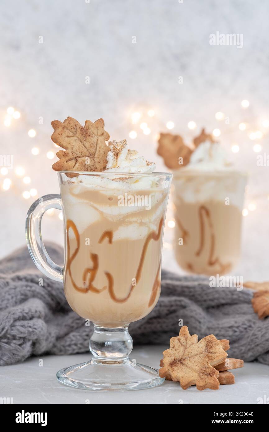 Pumpkin spice latte in a glass mug with caramel and cinnamon cookies with Autumn decoration Stock Photo