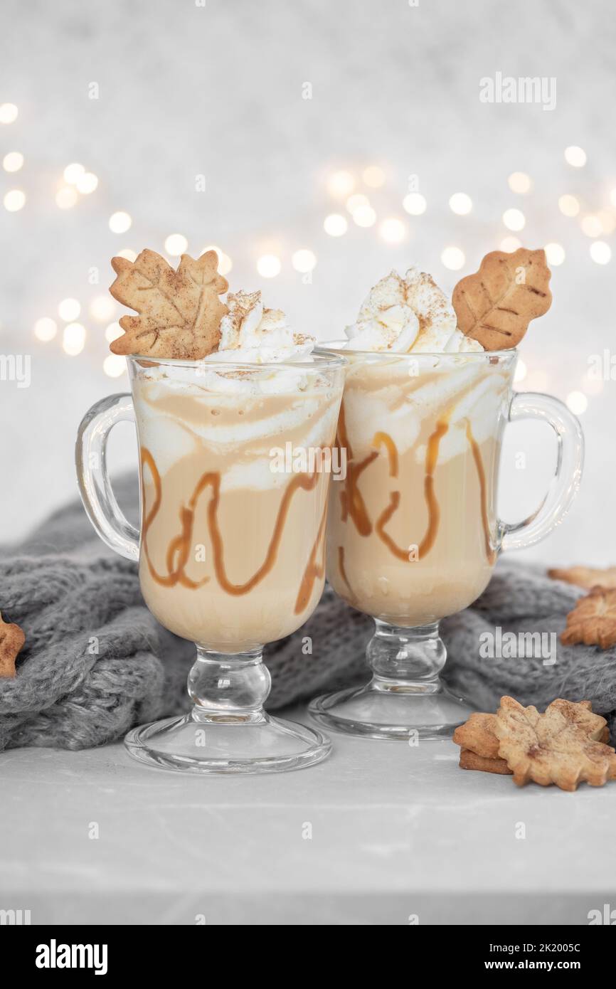 Pumpkin spice latte in a glass mug with caramel and cinnamon cookies with Autumn decoration Stock Photo