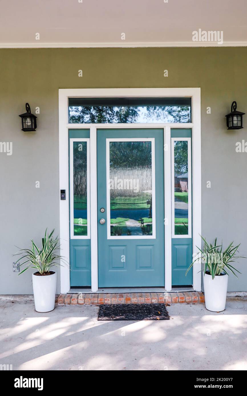 The front door to an Acadia style gray house with a turquoise door with transom windows. Stock Photo