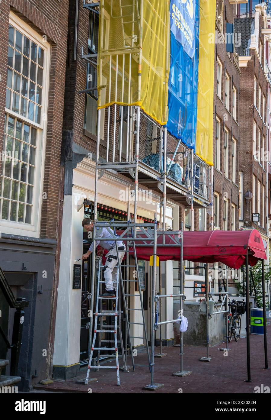 Man painting a wall of a shop in Amsterdam Stock Photo