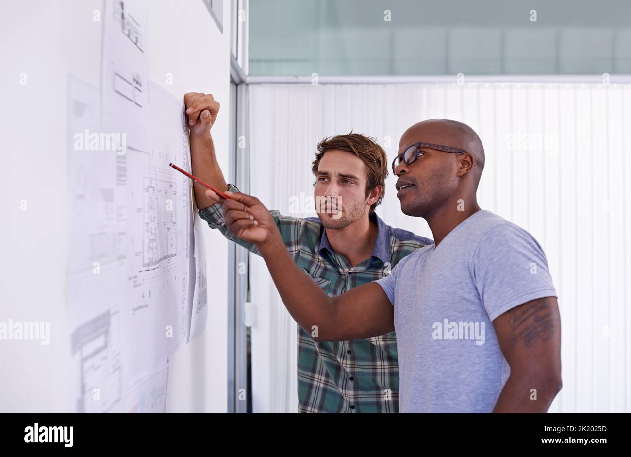 Are these measurements correct. two male architects examining and discussing building plans. Stock Photo
