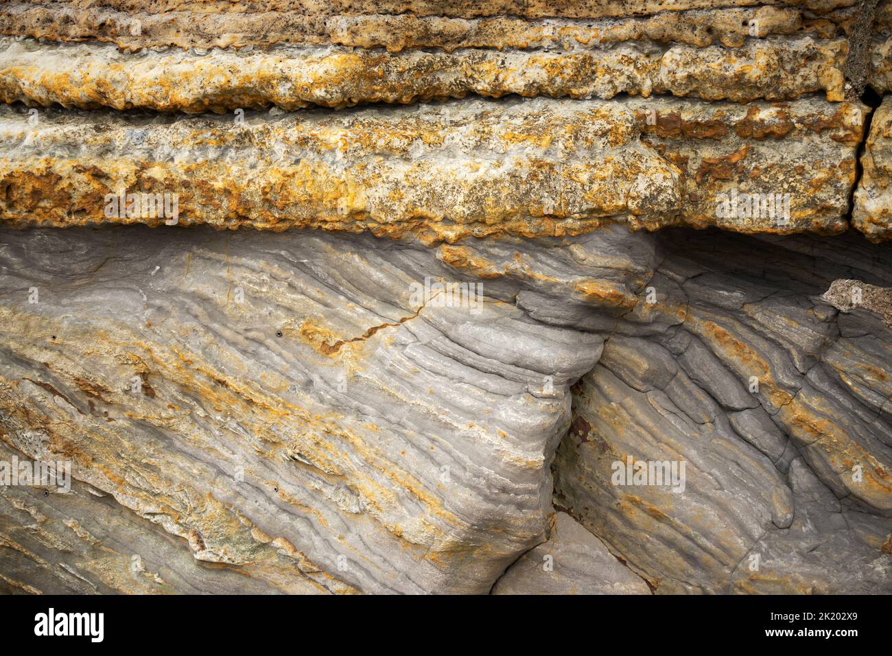 This Jurassic sedimentary strata shows a feature known as an Unconformity. The underlying darker mudstones have been titled and then the overlain Stock Photo