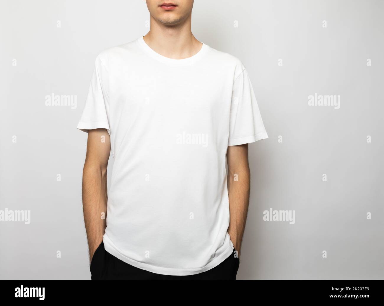 Relaxed young man wearing blank white cotton T-Shirt. Studio shot on gray background Stock Photo