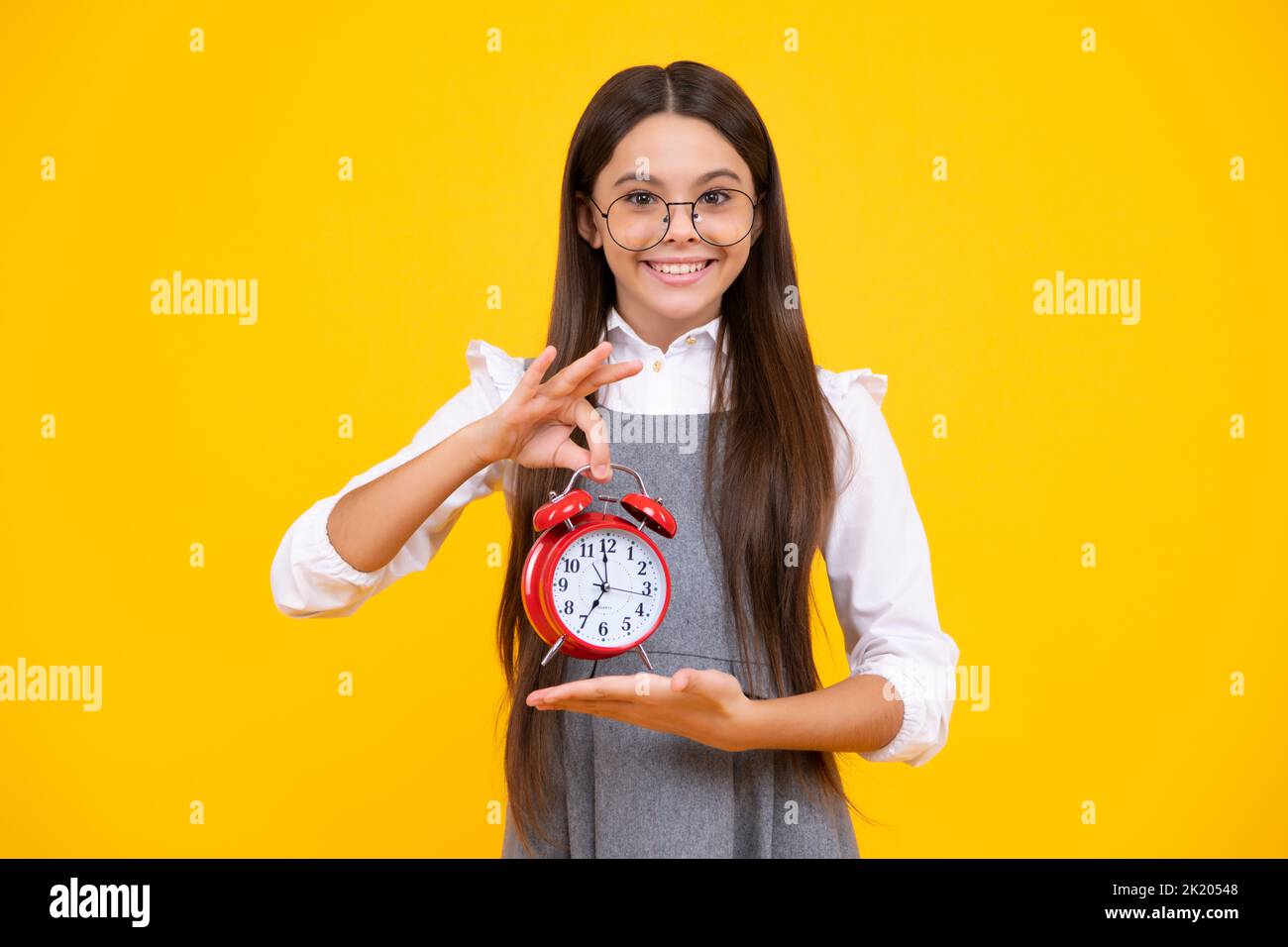 Punctual teen girl checking time. Child with alarm clock showing time. Happy face, positive and
