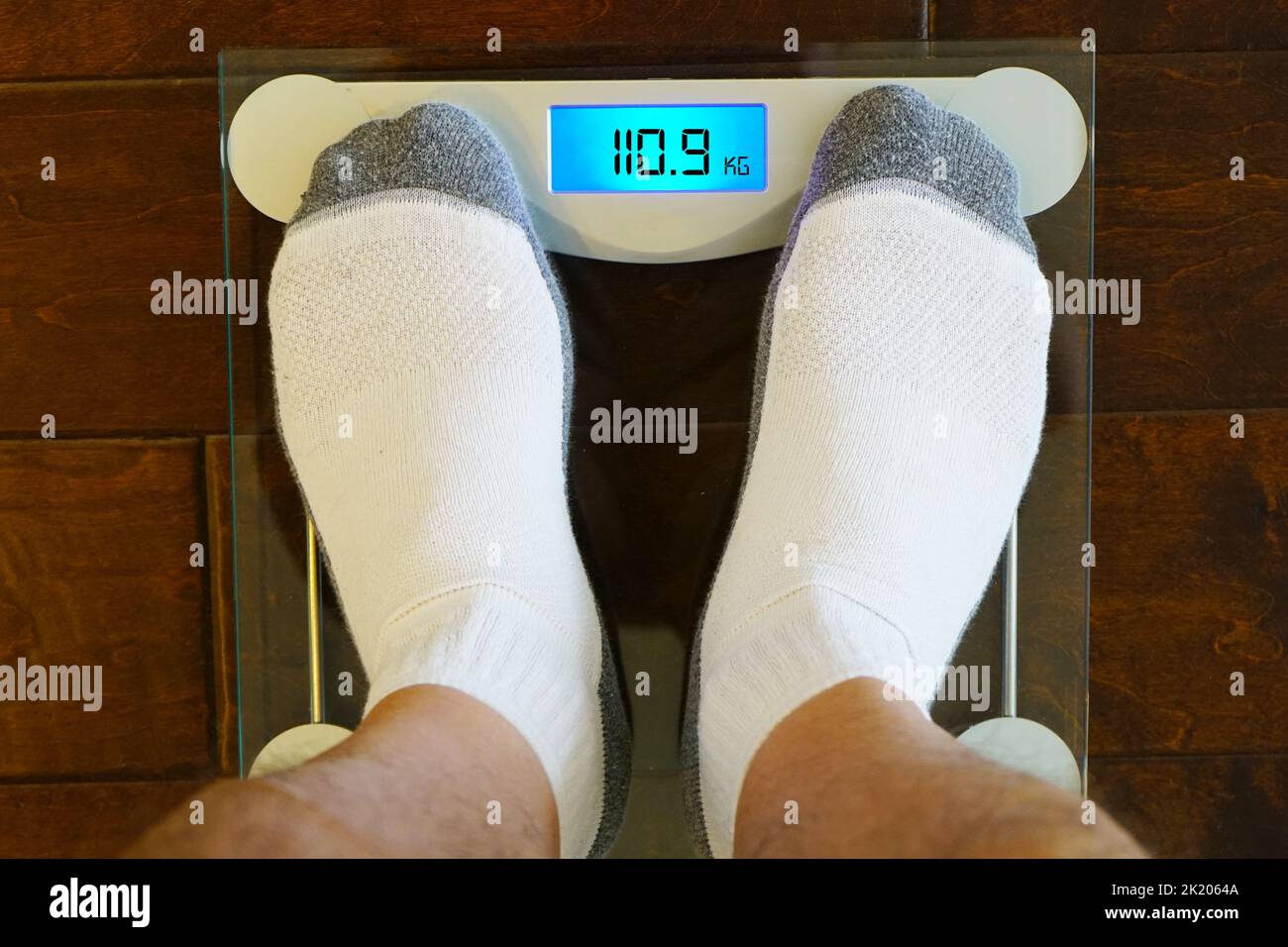 https://c8.alamy.com/comp/2K2064A/man-standing-on-the-digital-weight-scale-with-unhealthy-weight-in-kilograms-2K2064A.jpg