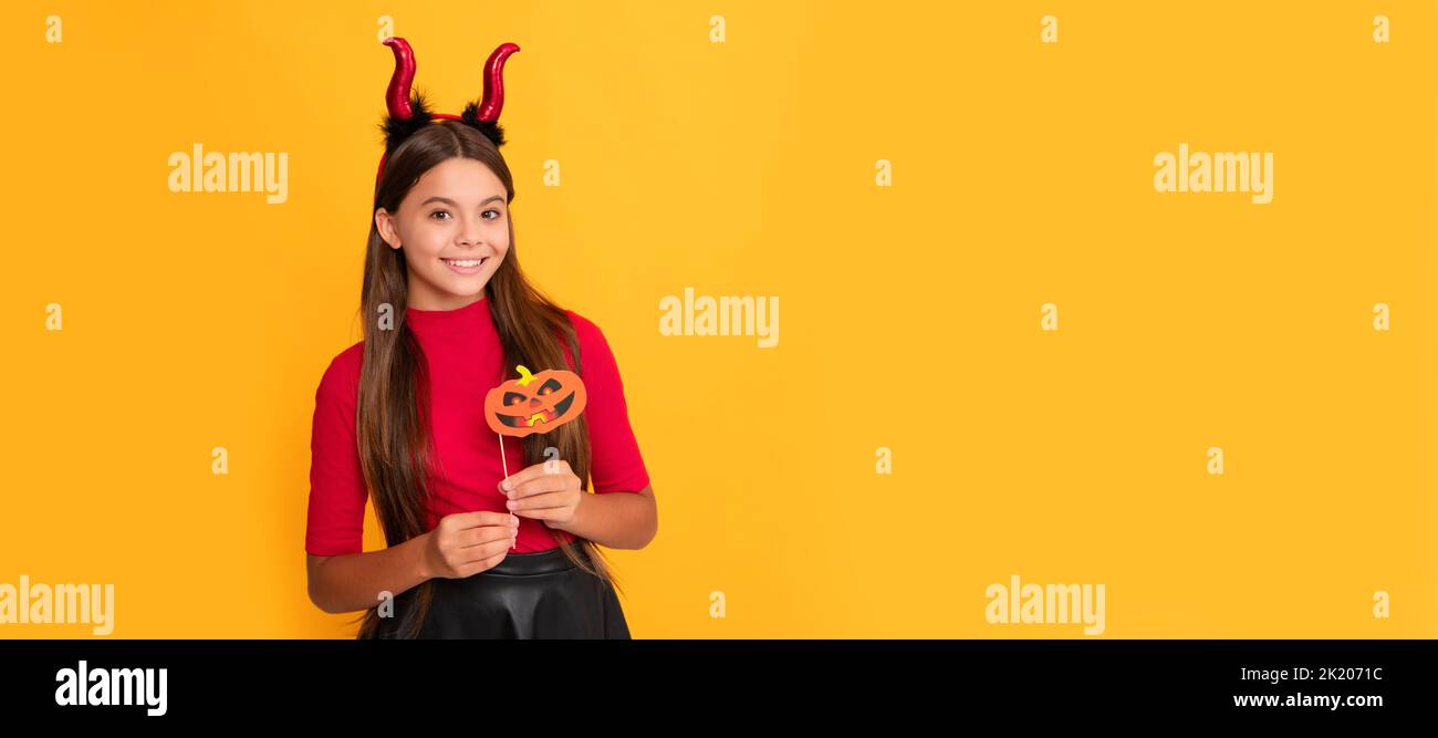 happy kid with pumpkin party accessory wearing devil horns on yellow
