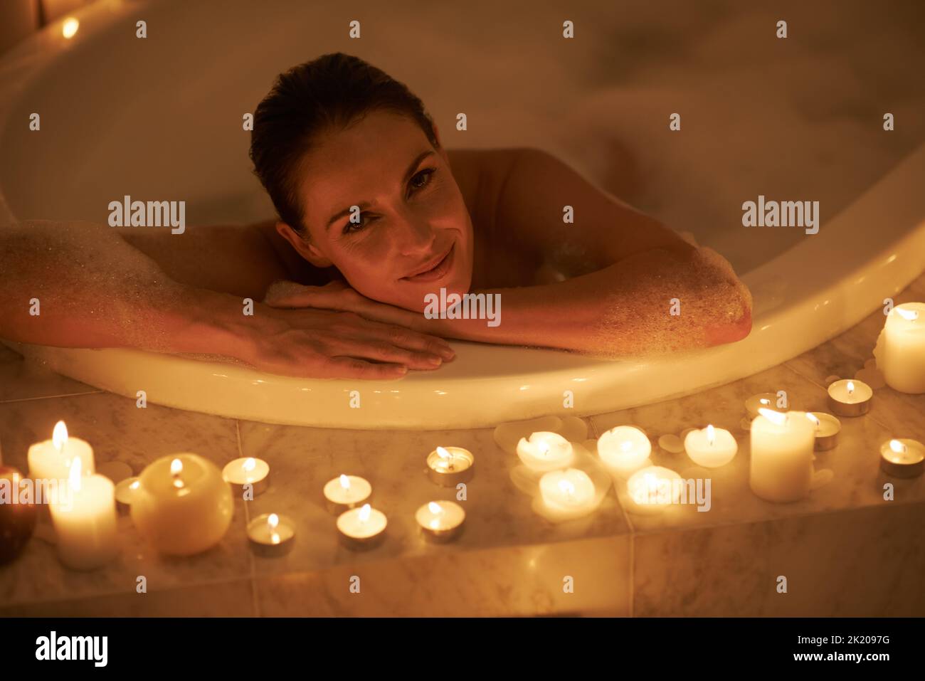 Nothing relaxes one better than a bubble bath. a gorgeous woman relaxing in a candle lit bath. Stock Photo