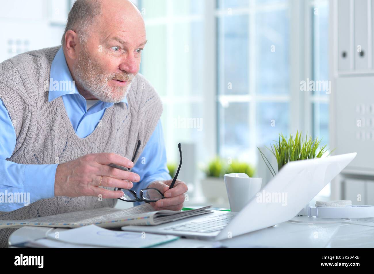 Emotional senior man reading newspaper at home Stock Photo