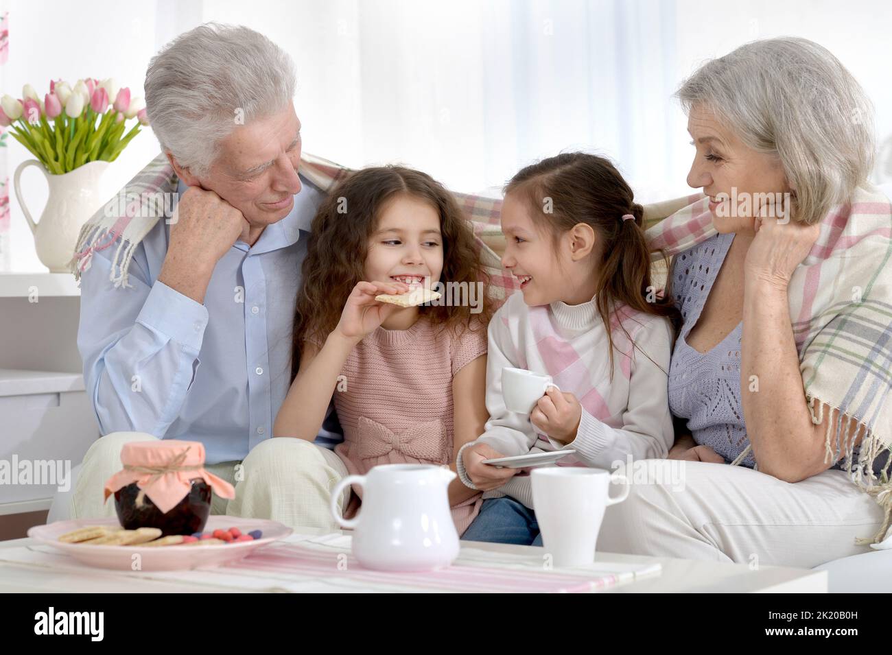 Grandfather and grandmother together with granddaughters drink tea Stock Photo