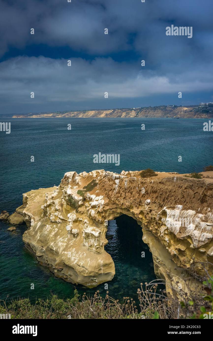 The shore line of the La Jolla Cove with a cave and a landscape in the background with a cloudy sky. Stock Photo