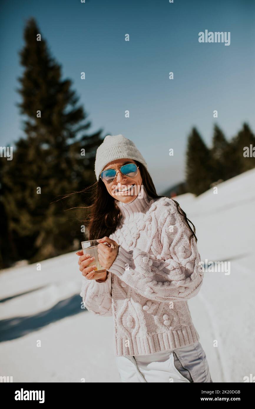 Young woman drinking lemonade  on the mountain ski track on a sunny winter day Stock Photo