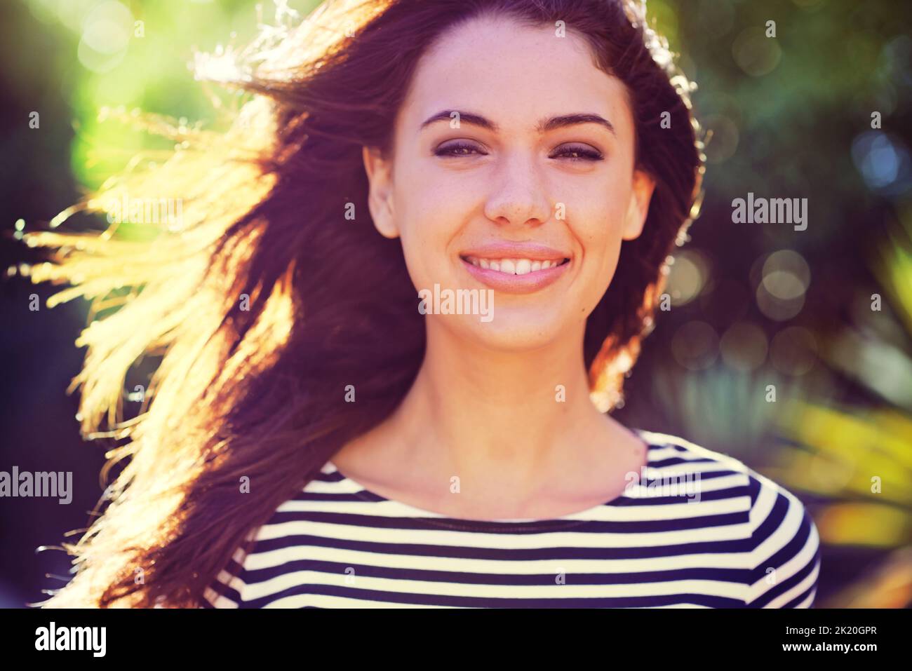 Shes a free spirit. Portrait of a beautiful young woman standing in the sunlight outdoors. Stock Photo