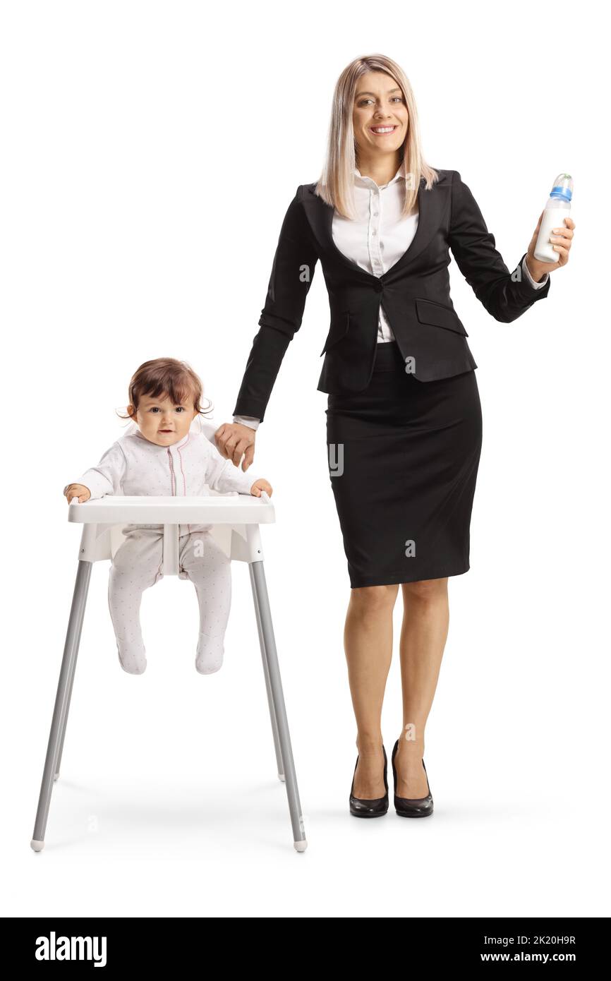 Businesswoman holding a bottle of water and standing next to baby in a feeding chair isolated on white background Stock Photo