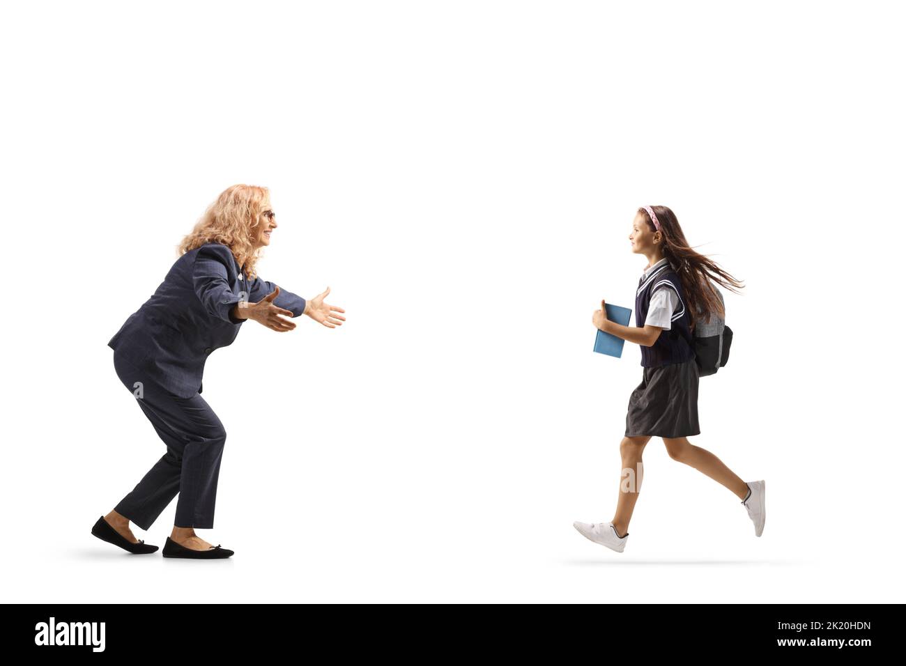 Schoolgirl holding a book and running to hug a woman isolated on white background Stock Photo