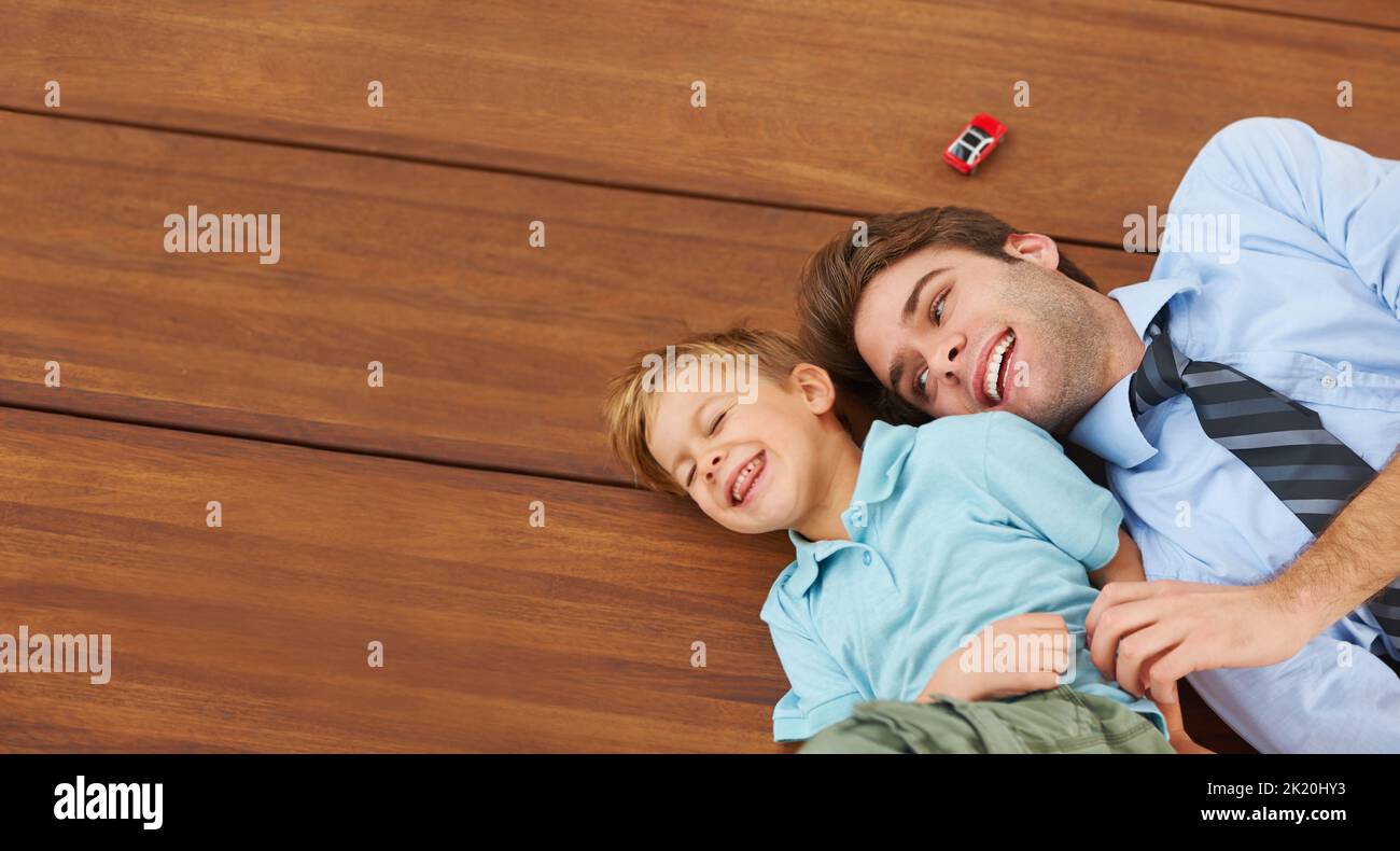 So glad Dads home. A little boy playing with his father on the floor. Stock Photo