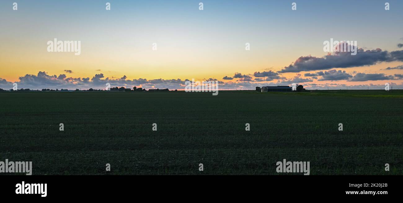 Panoramic view of clouds over agricultural landscape after sunset. Stock Photo