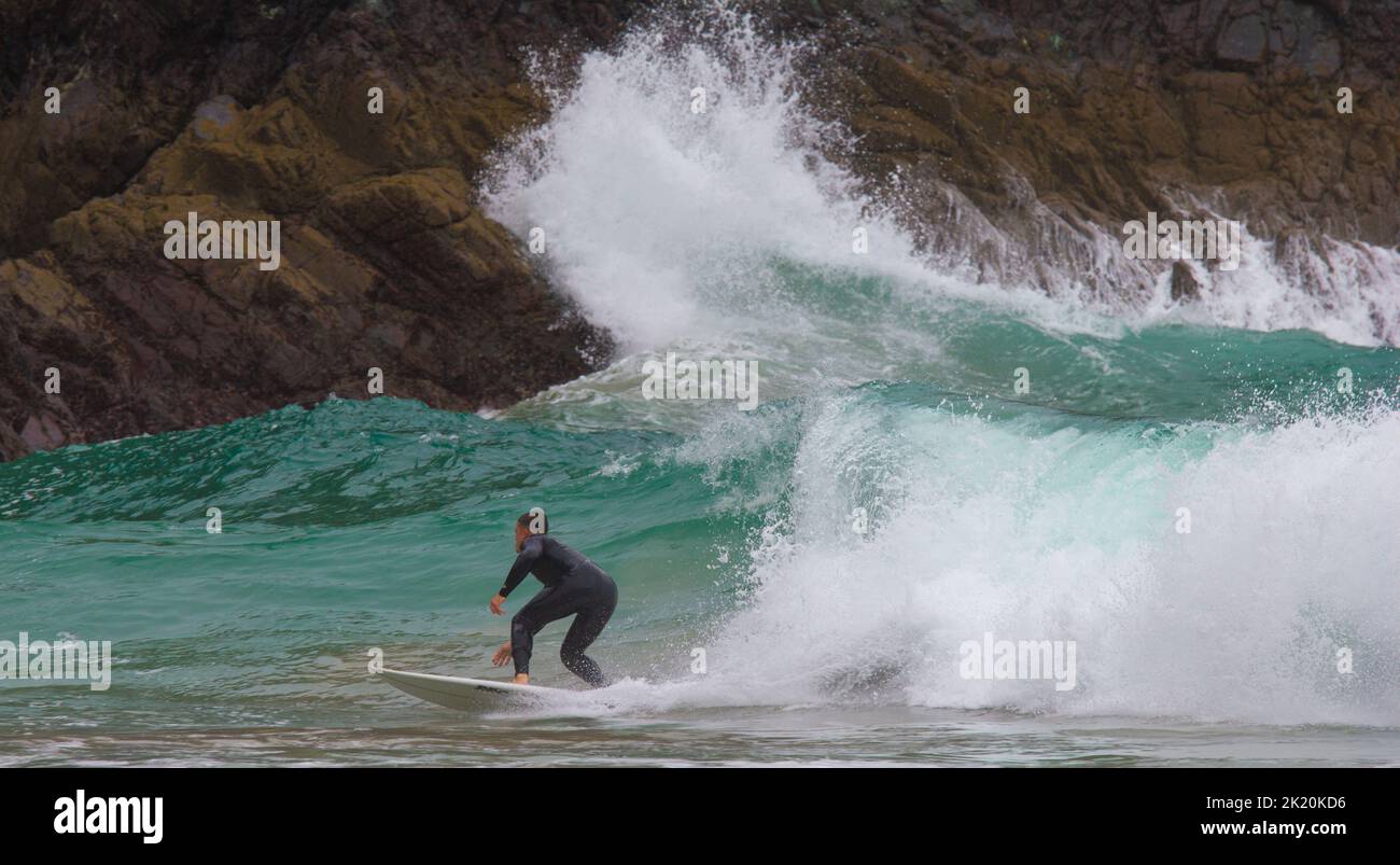 A surfer in the surf at Kynance Cove on the Lizard Peninsula, Cornwall