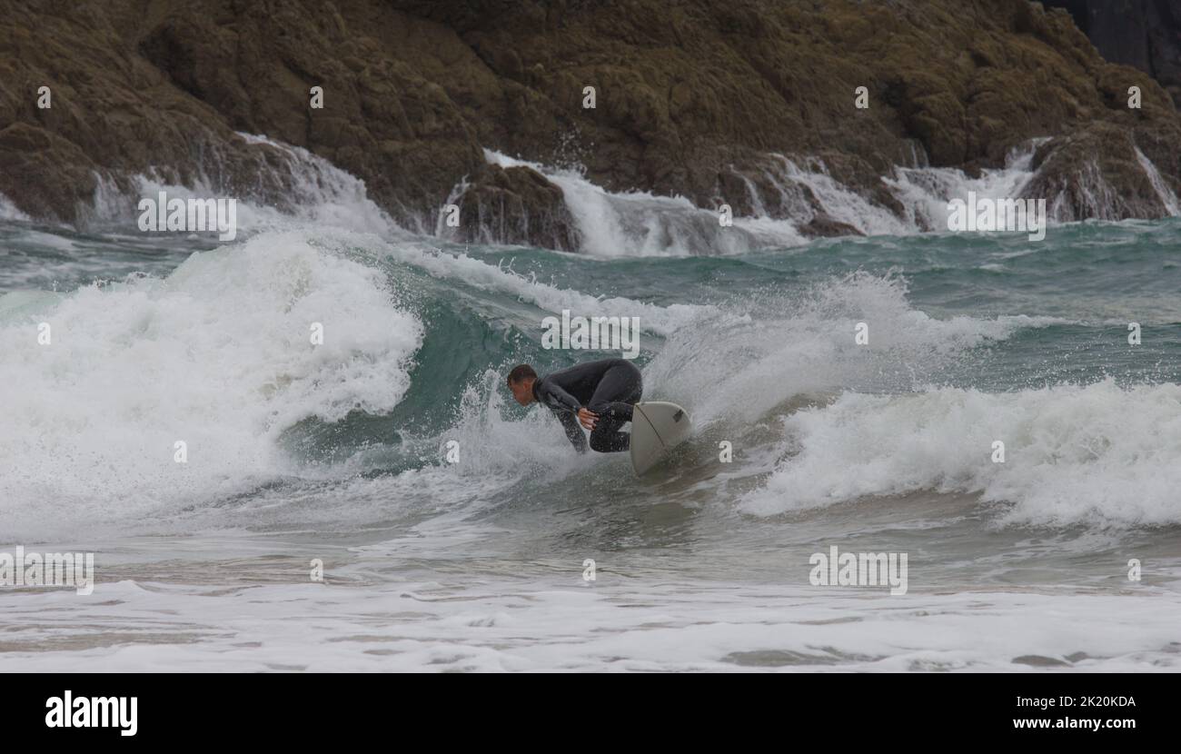 A surfer in the surf at Kynance Cove on the Lizard Peninsula, Cornwall, England Stock Photo