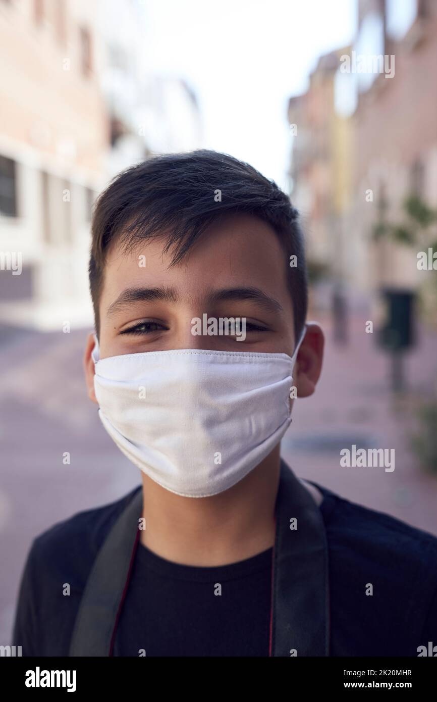 A cute little kid with green eyes wearing a mask . Stock Photo