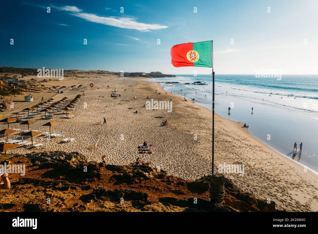 Portuguese flag waving over blue sky and ocean, Guincho Beach, Portugal Stock Photo