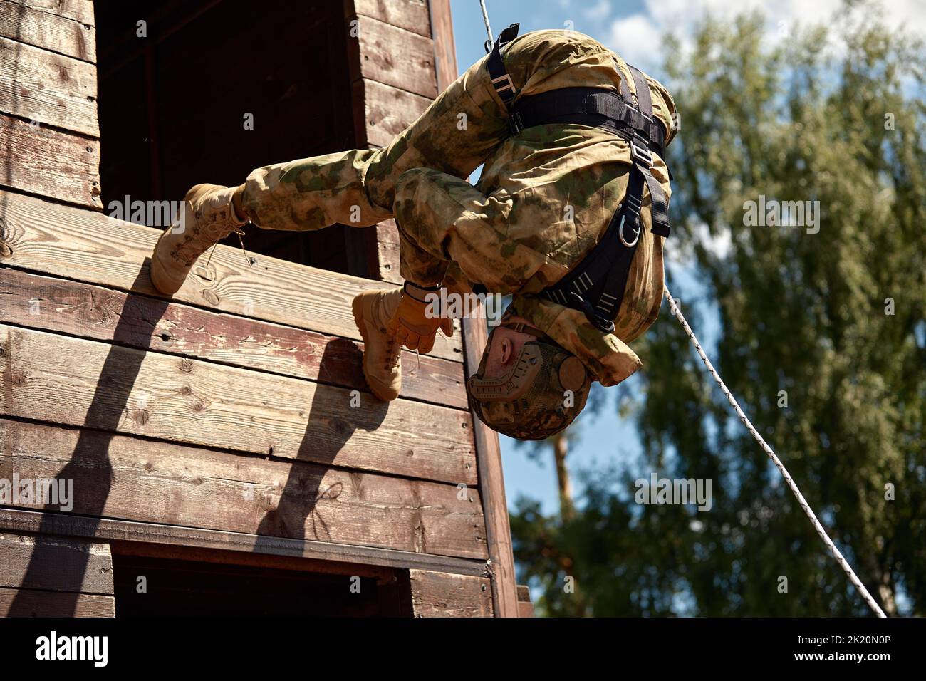 Soldier training rappel with rope. Military man does hanging on climbing equipment Stock Photo