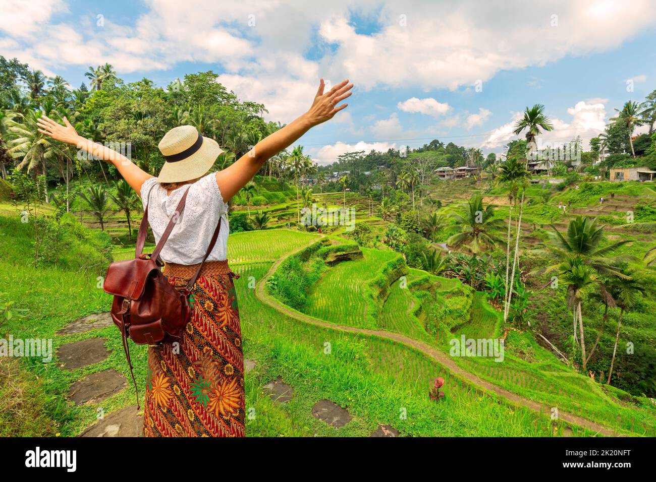 Young girl with hat standing with open arms looking the ricefields. Rice terraces famous place Tegallalang near Ubud. The island Bali in indonesia in Stock Photo