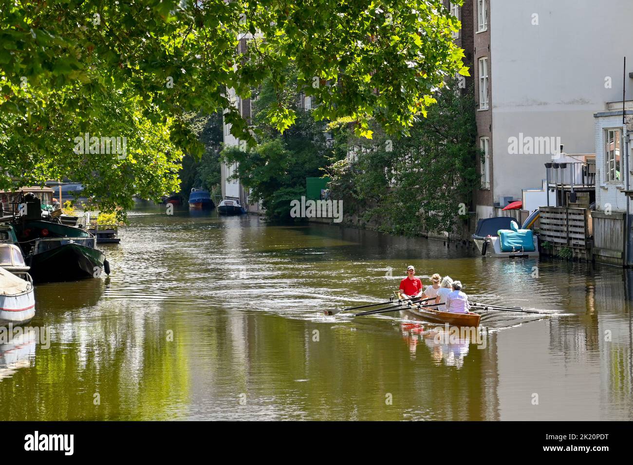 Amsterdam, Netherlands - August 2022: Rowing boat with mature women exercising on a canal in the city centre Stock Photo