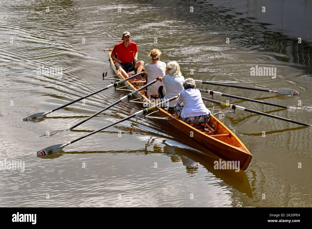 Amsterdam, Netherlands - August 2022: Rowing boat with mature women exercising on a canal in the city centre Stock Photo