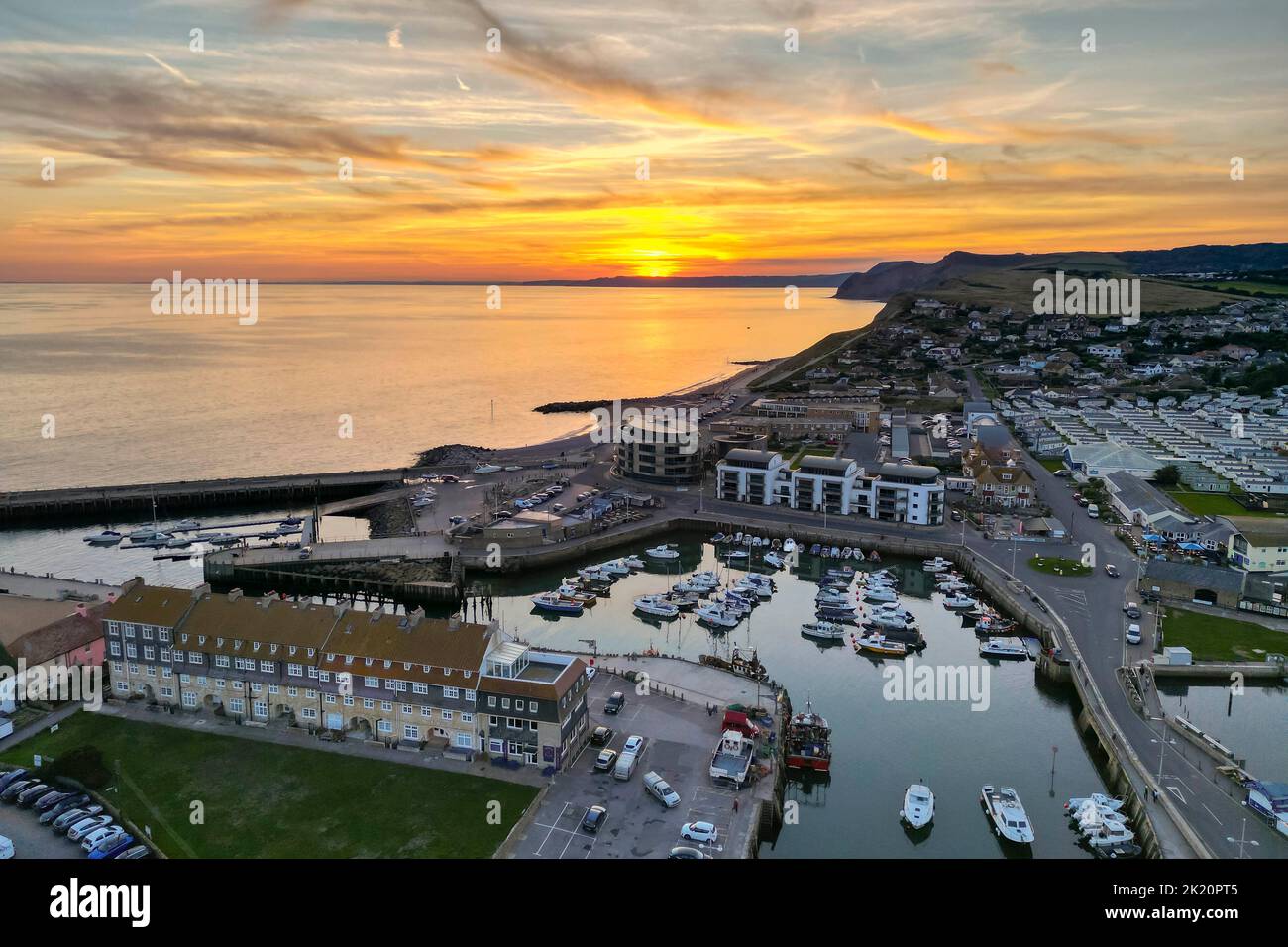 West Bay, Dorset, UK.  21st September 2022.  UK Weather.  View from the air of the spectacular orange sunset above the harbour at the seaside resort of West Bay in Dorset at the end of a hot sunny autumn day. Picture Credit: Graham Hunt/Alamy Live News Stock Photo