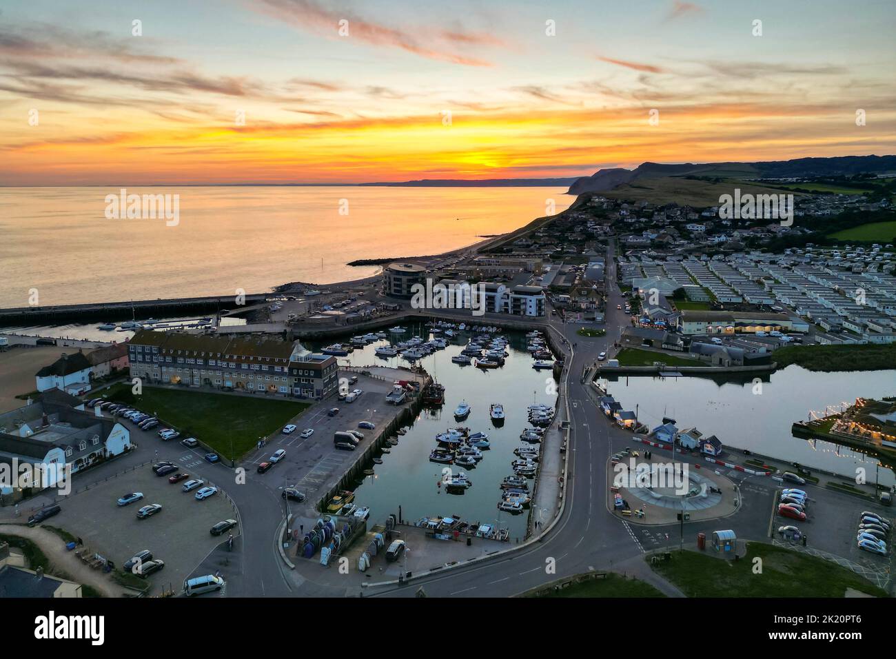 West Bay, Dorset, UK.  21st September 2022.  UK Weather.  View from the air of the spectacular orange sunset above the harbour at the seaside resort of West Bay in Dorset at the end of a hot sunny autumn day. Picture Credit: Graham Hunt/Alamy Live News Stock Photo