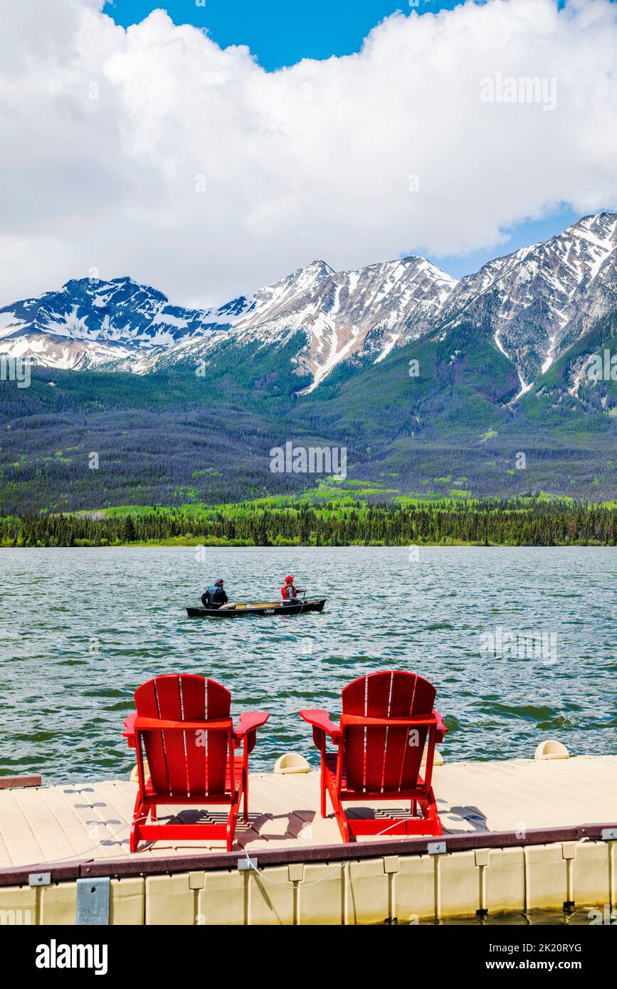 Tourists paddle canoe; dock & Adirondack chairs; Pyramid Lake; Jasper