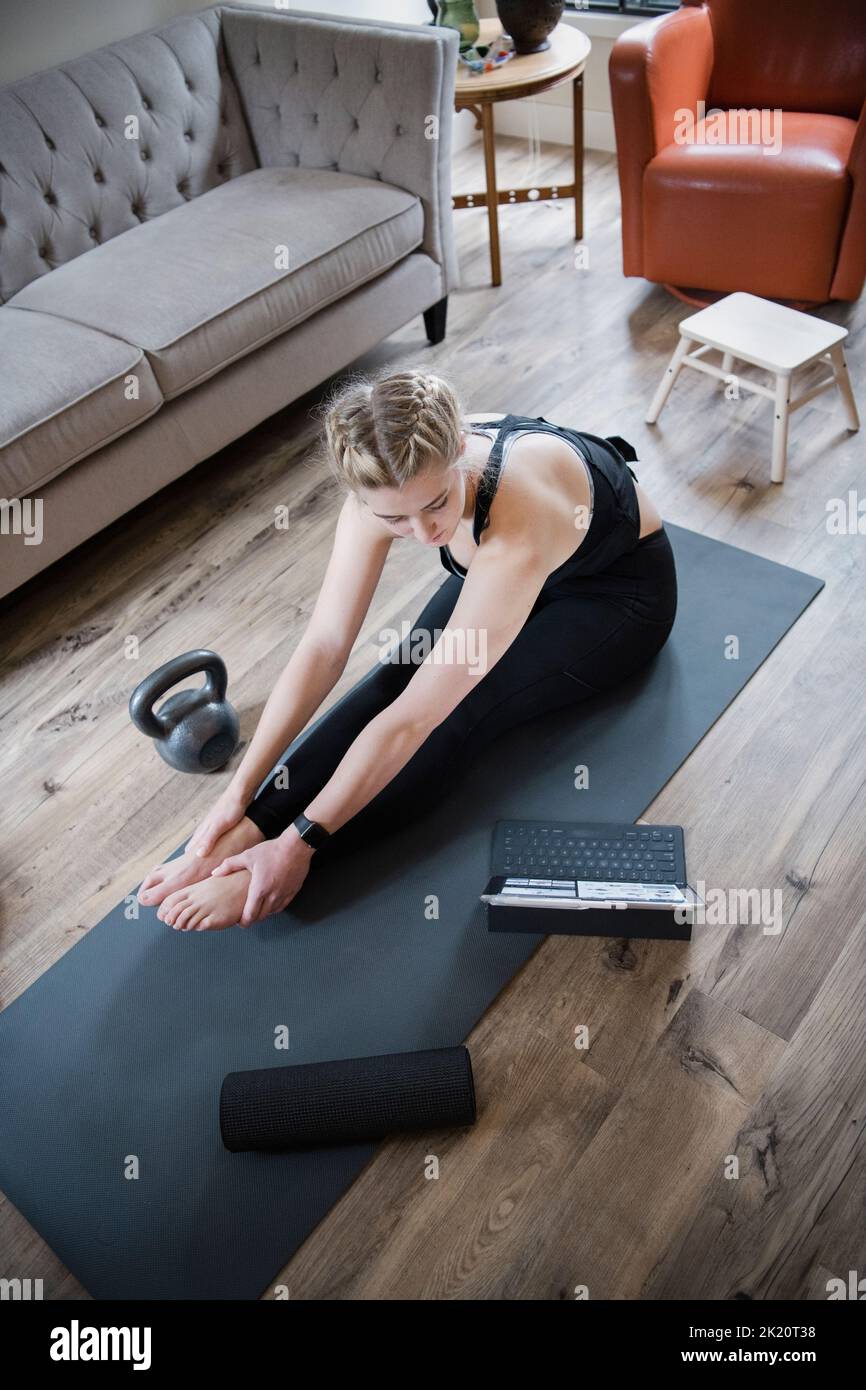 Young woman with digital tablet taking online exercise class at home Stock Photo