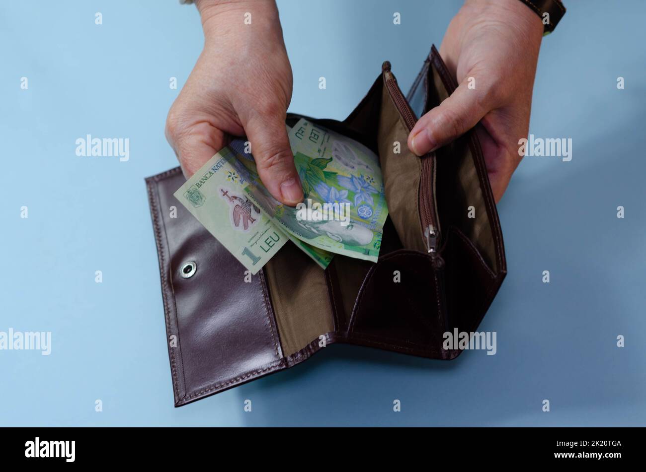 Hands of elderly woman with money ron on wallet on blue background. Concept of poverty in retirement Stock Photo