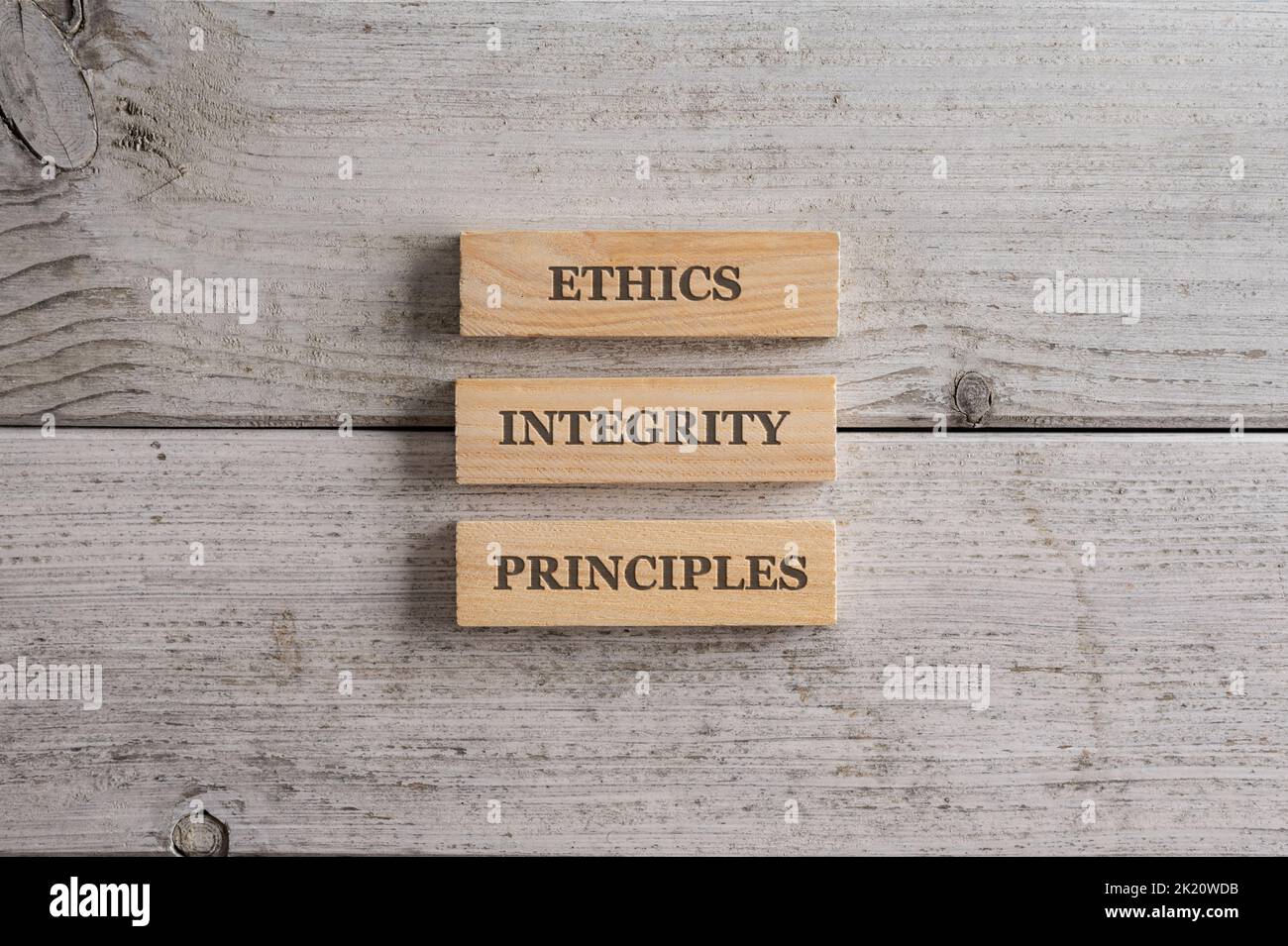 Words Ethics, Integrity and Principles written on three stacked wooden blocks placed over white wooden background. Stock Photo