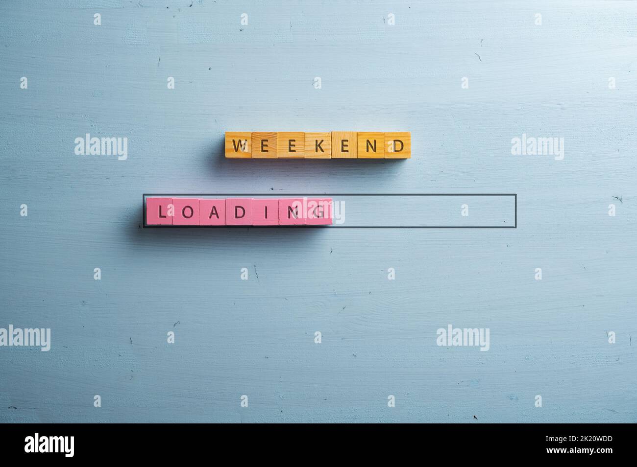 Weekend loading sign spelled on pink and brown wooden blocks in a loading bar. Over blue wooden background. Stock Photo