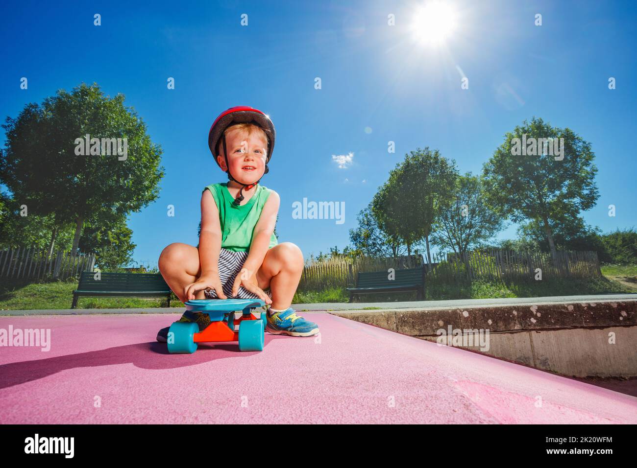 Smiling handsome little boy sit on the skate at skatepark Stock Photo