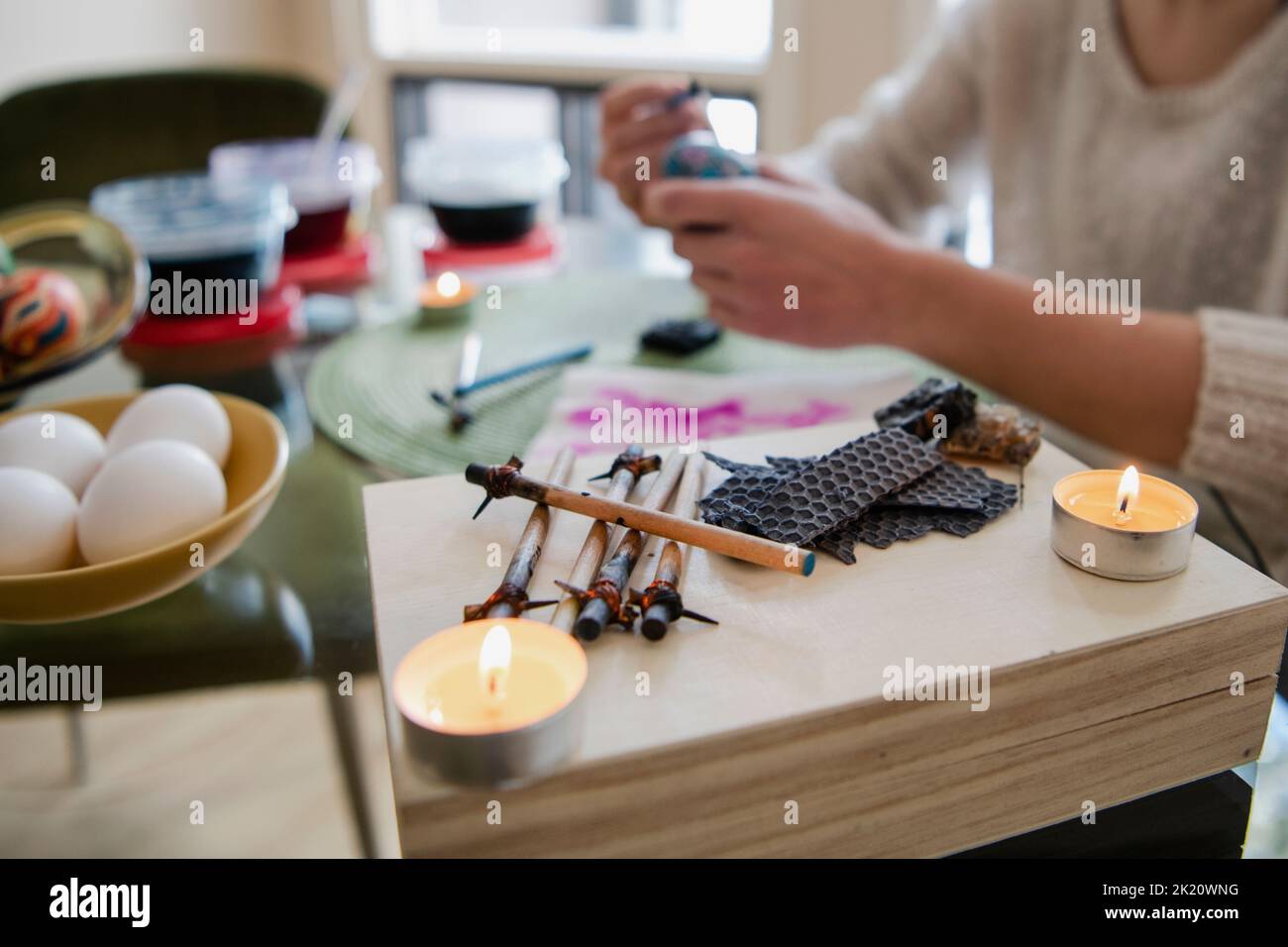 Young woman using wax and candles to decorate Pysanka Easter eggs Stock