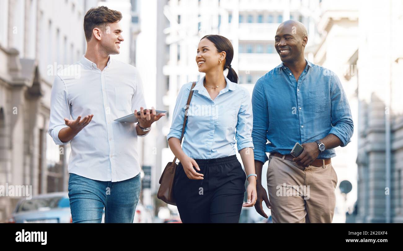 Startup entrepreneur, friends or corporate workers discuss project while walking in the city. Diversity, happy and business people talking, walk and Stock Photo