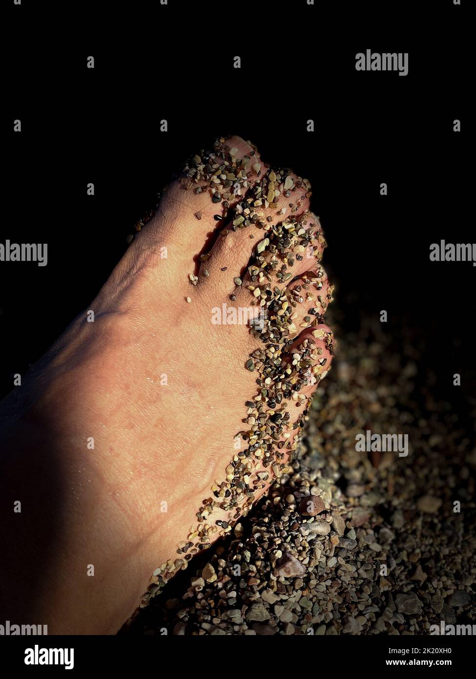 A foot covered in sand by the sea. Stock Photo
