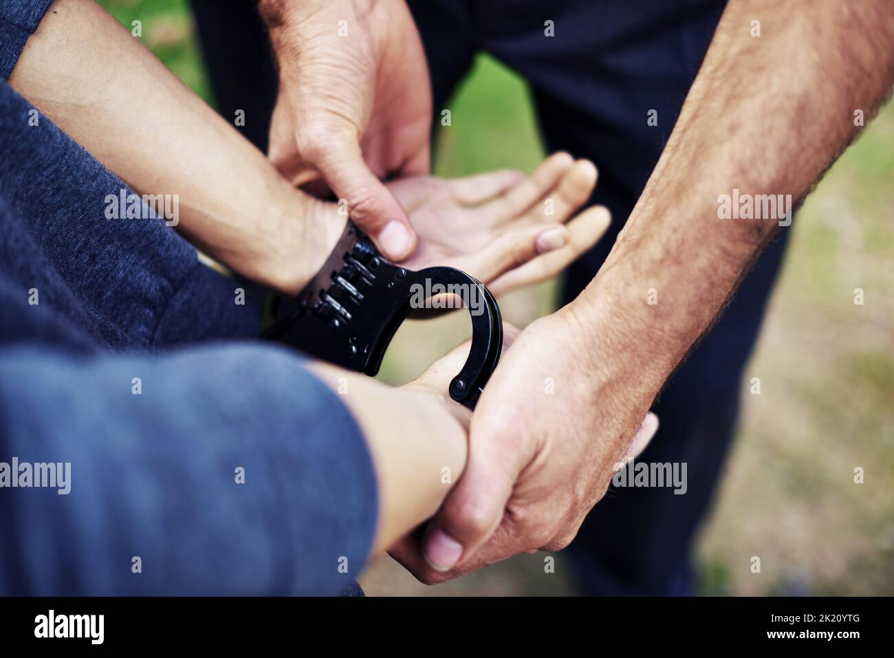 Keeping crime off the streets. a policemans hands putting cuffs on a suspect. Stock Photo