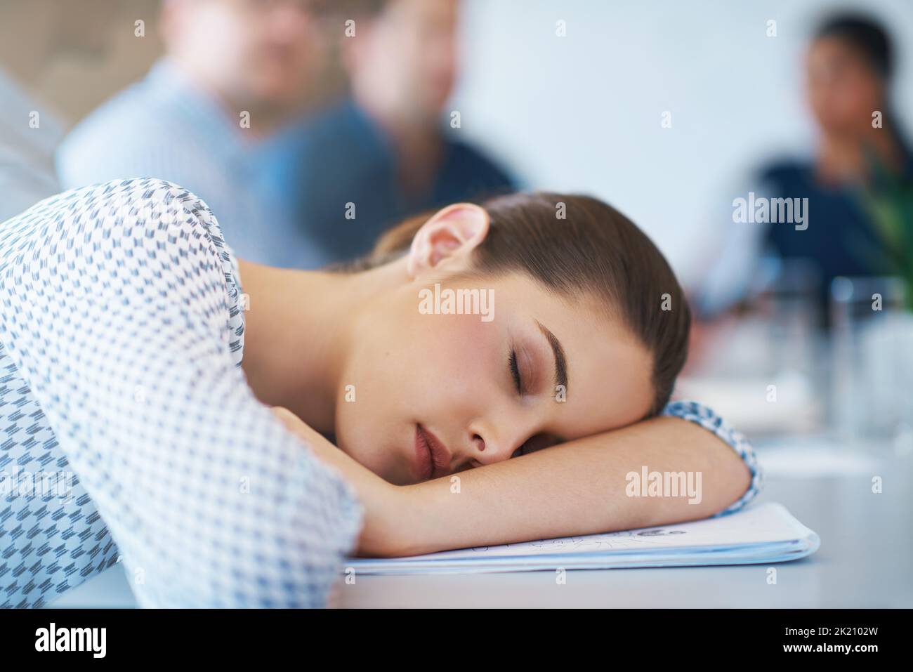 She ran out of steam...An exhausted businesswoman lying with her head on her arms during a meeting. Stock Photo