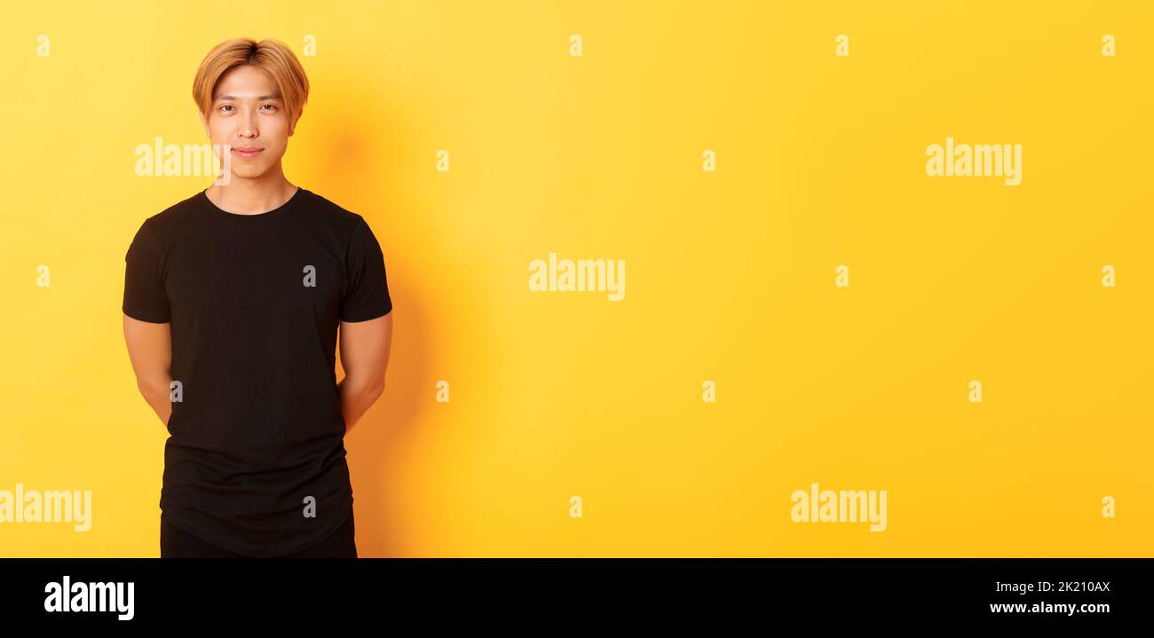 Portrait of handsome smiling asian blond guy looking sassy, holding ...