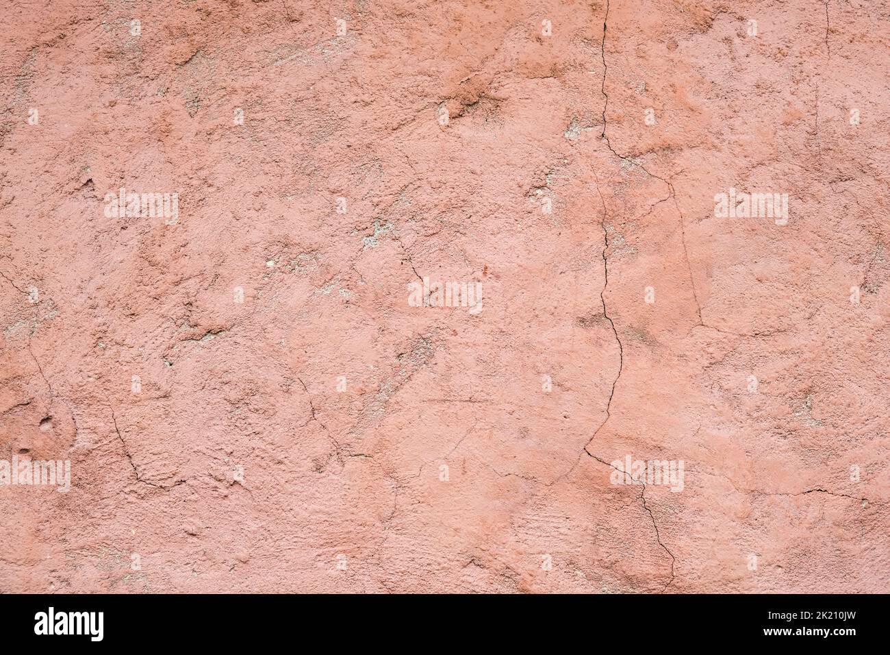 The texture of old painted concrete. The concrete background is dusty pink. The background of a painted wall with cracks. Stock Photo