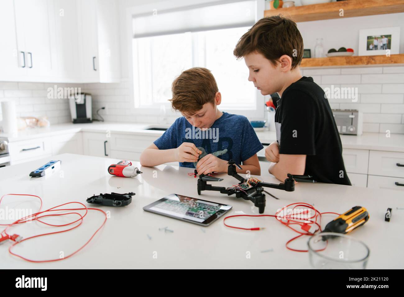 Brothers learning to assemble drone at kitchen counter Stock Photo
