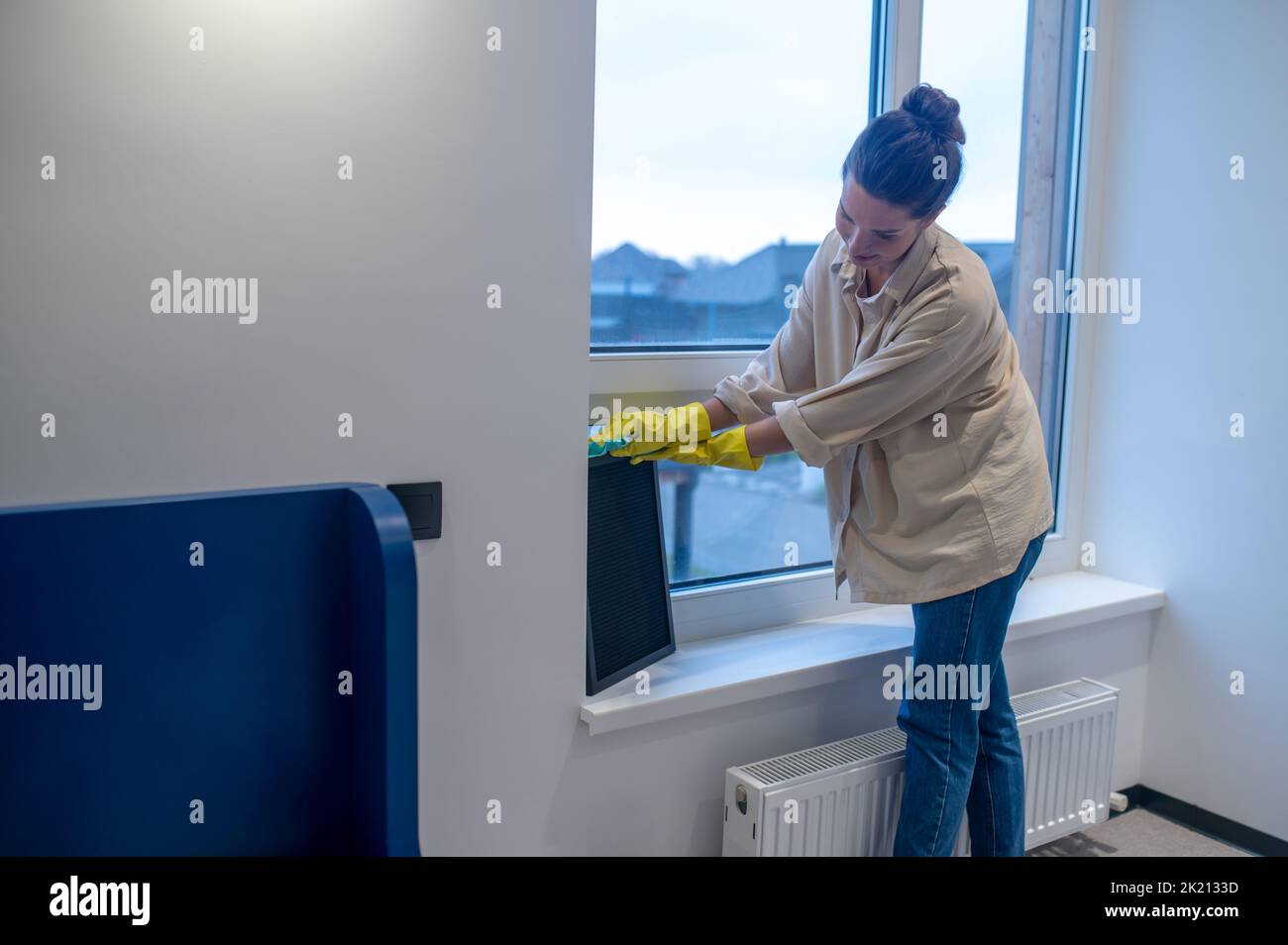 Focused cleaning lady busy dusting the room Stock Photo