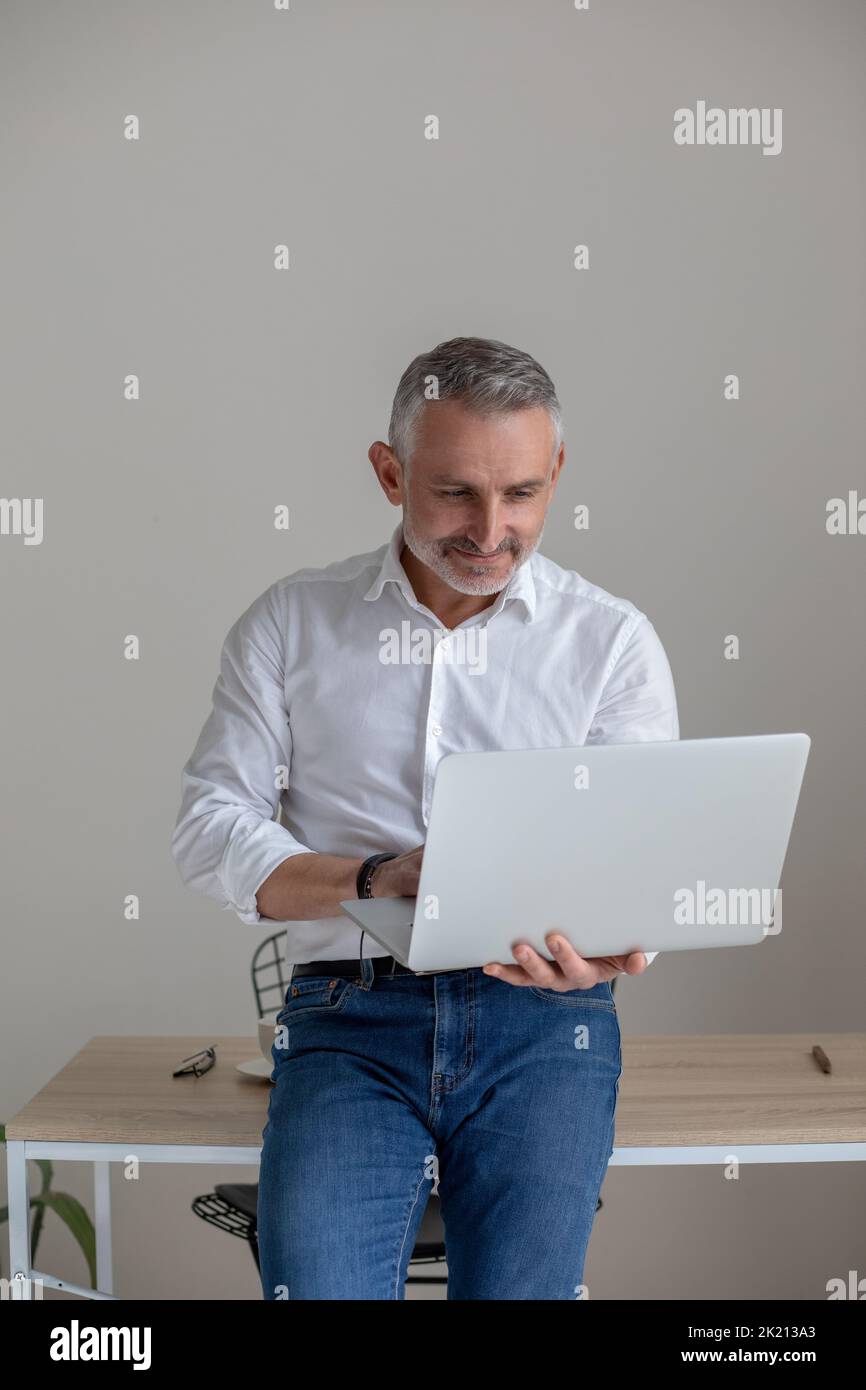 Gray-haired mid aged businessman with a laptop in hands Stock Photo