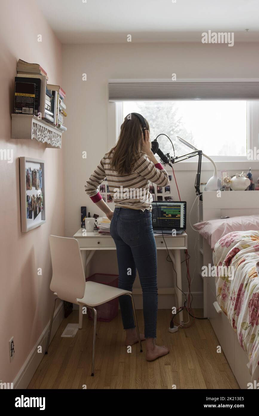 Teenage girl singing and recording in bedroom Stock Photo