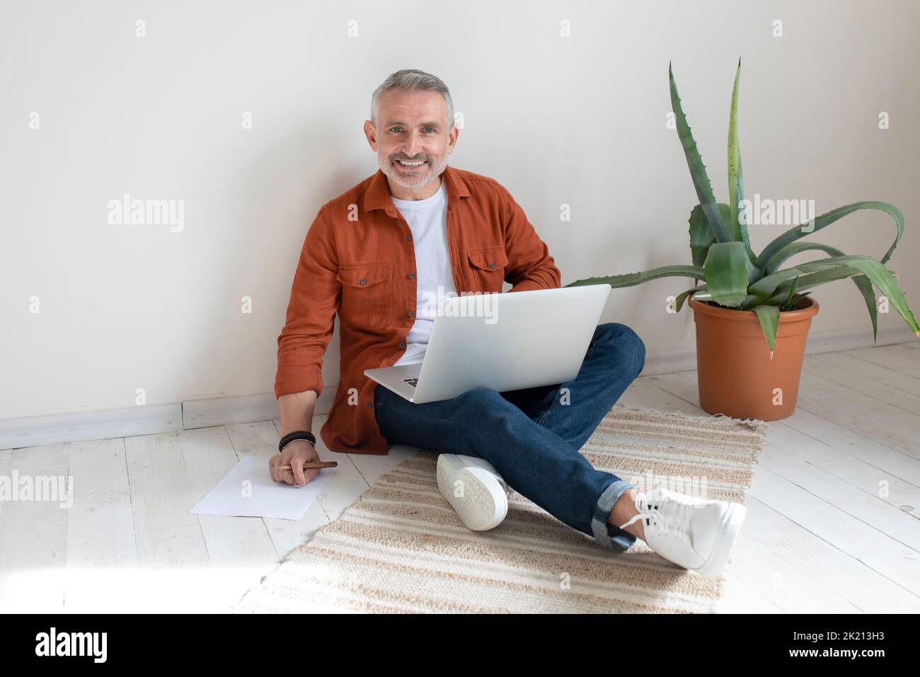 Bearded man in terracotta shirt working from home Stock Photo