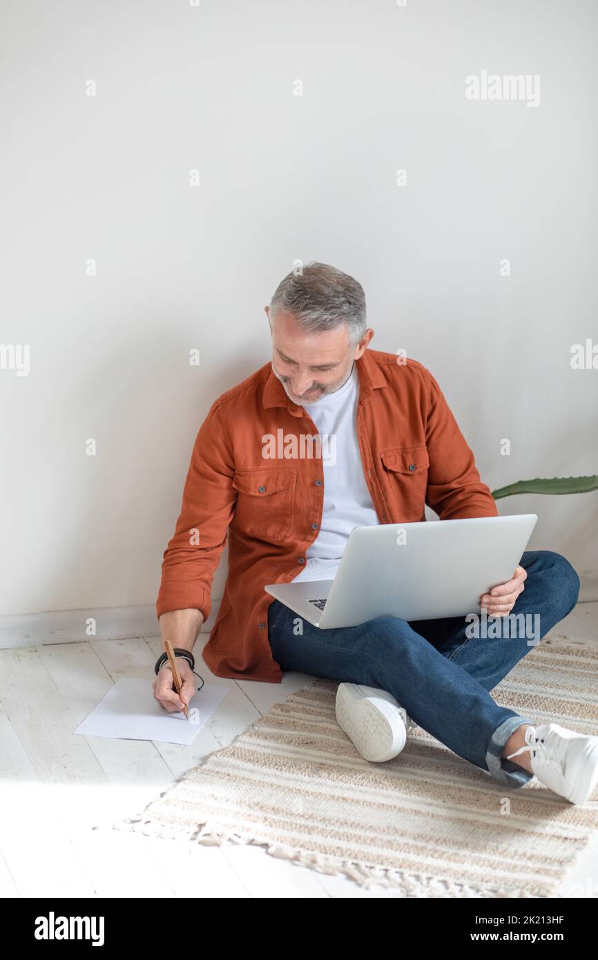 Bearded man in terracotta shirt working from home Stock Photo