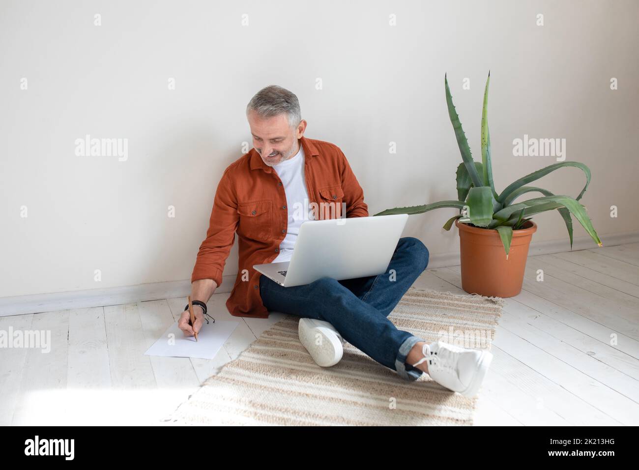 Businessman sitting on the floor in the home office and making notes Stock Photo